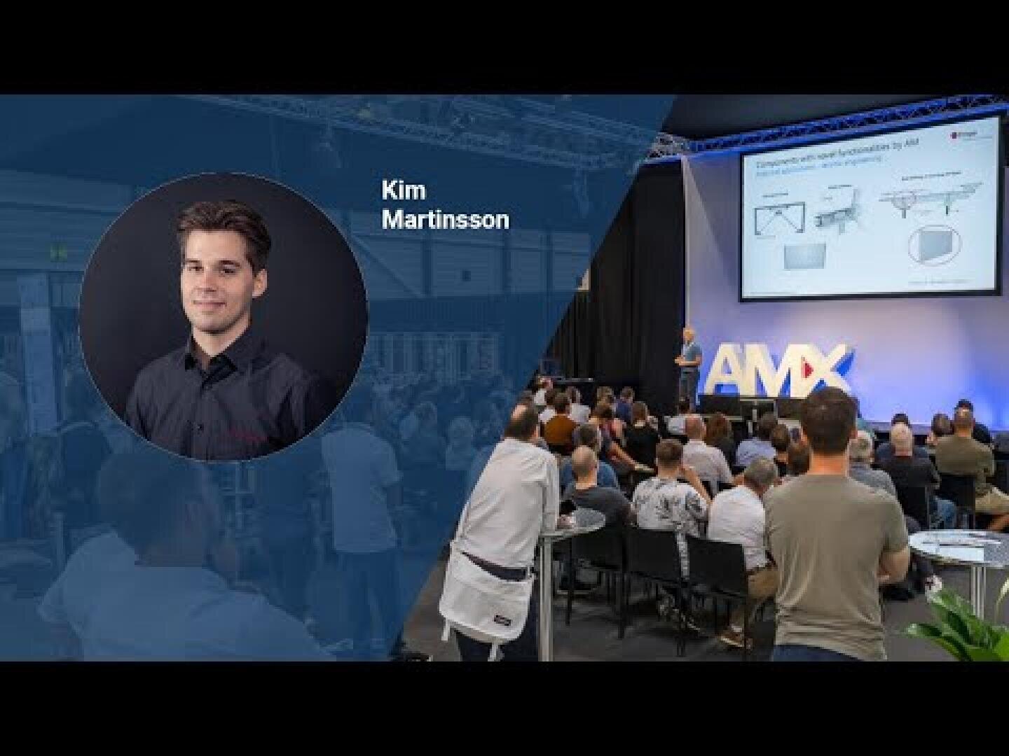 Ein Konferenzraum mit einem Publikum, das einer Bühne gegenübersteht, auf der eine Person Dias präsentiert. Auf der linken Seite ist ein Porträt von Kim Martinsson mit seinem Namen abgebildet. Die Bühne ist mit AMX-Buchstaben beschriftet und die Präsentationsfolien werden projiziert.
