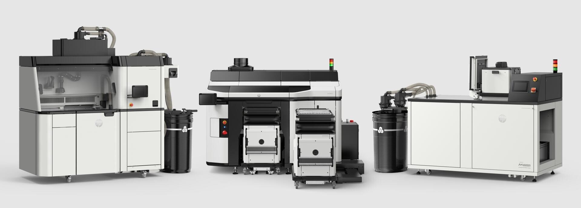 Drei große, industrielle 3D-Druckmaschinen mit weißen und schwarzen Bedienfeldern, Bildschirmen, Schläuchen und Behältern, die nebeneinander vor einem schlichten hellen Hintergrund angeordnet sind.