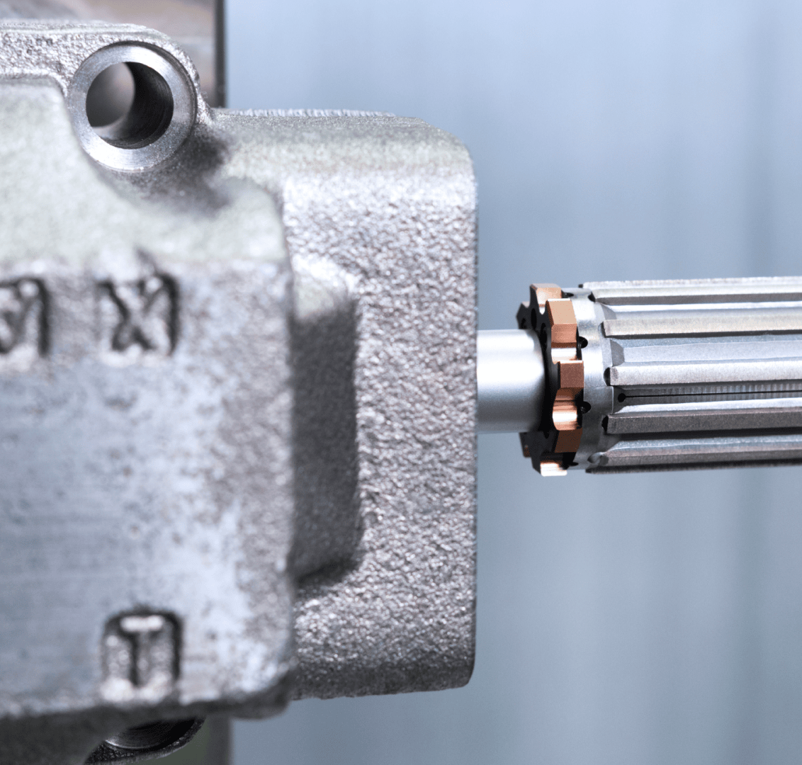 Close-up of a metal gearbox with a grooved shaft partially inserted into a housing, with detailed textures and industrial components in a light gray and metallic color scheme.