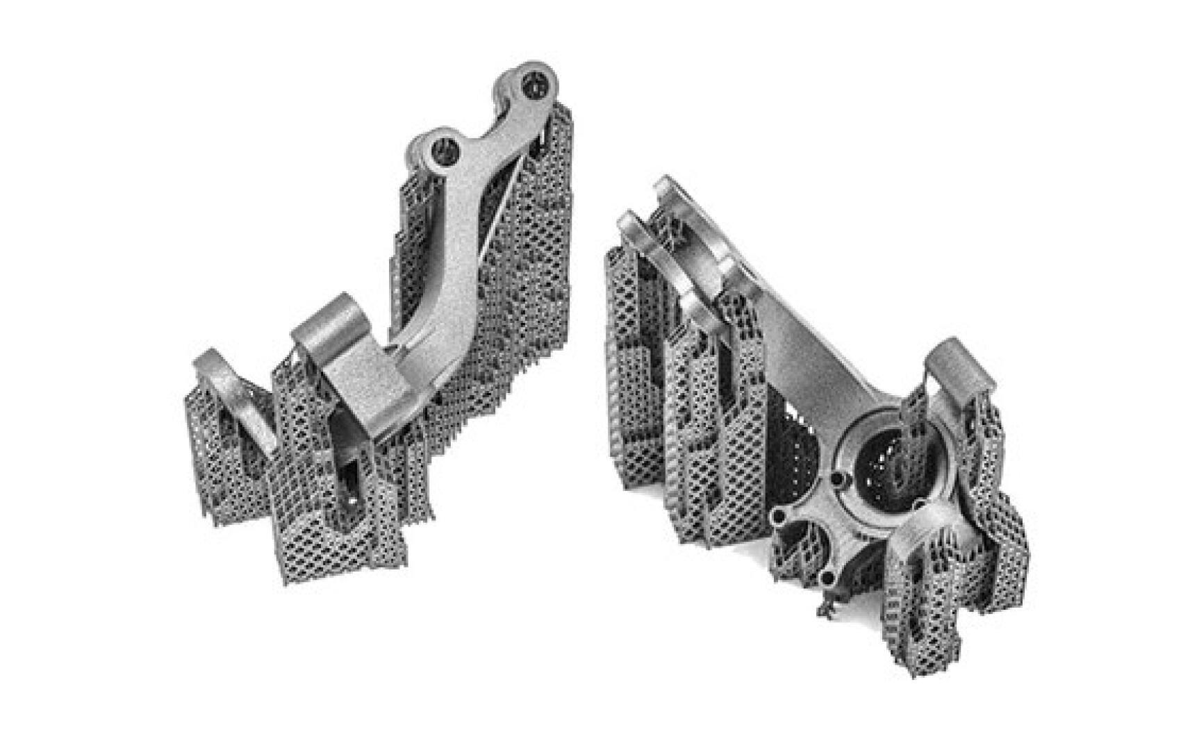 Zwei komplexe metallische 3D-gedruckte Teile mit komplizierten Gitterstützstrukturen werden nebeneinander vor einem weißen Hintergrund angezeigt.