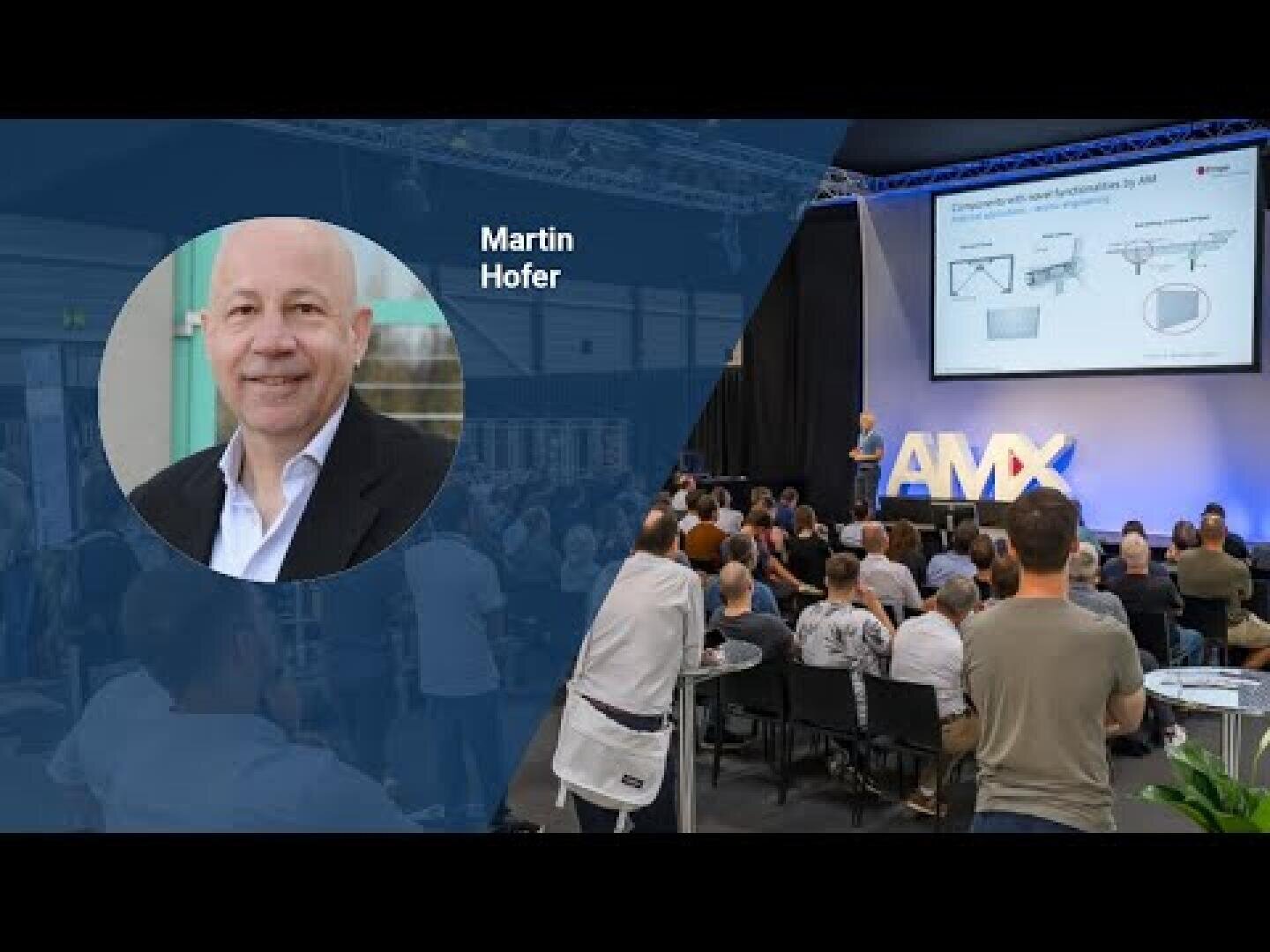 Ein Mann, identifiziert als Martin Hofer, ist in einem Porträt-Overlay auf der linken Seite zu sehen, während er auf der rechten Seite eine Präsentation vor einem sitzenden Publikum bei einer Veranstaltung mit AMX auf der Bühne hält.
