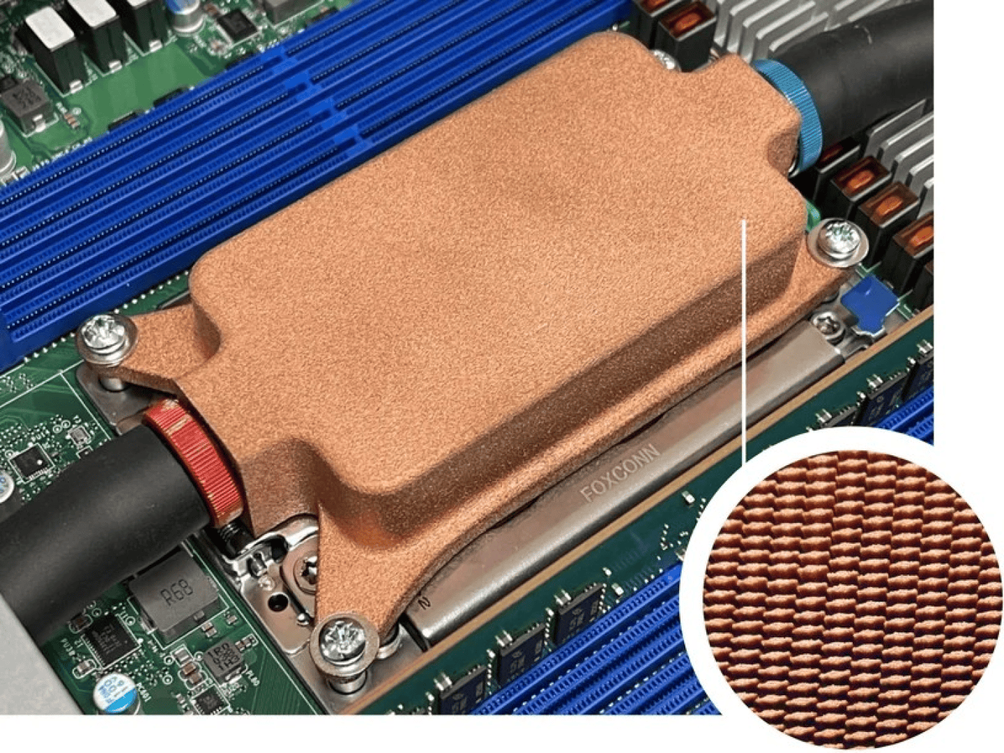Close-up of a copper liquid cooling block installed on a computer motherboard, with a circular cut-out showing an enlarged view of the finely textured surface of the copper.