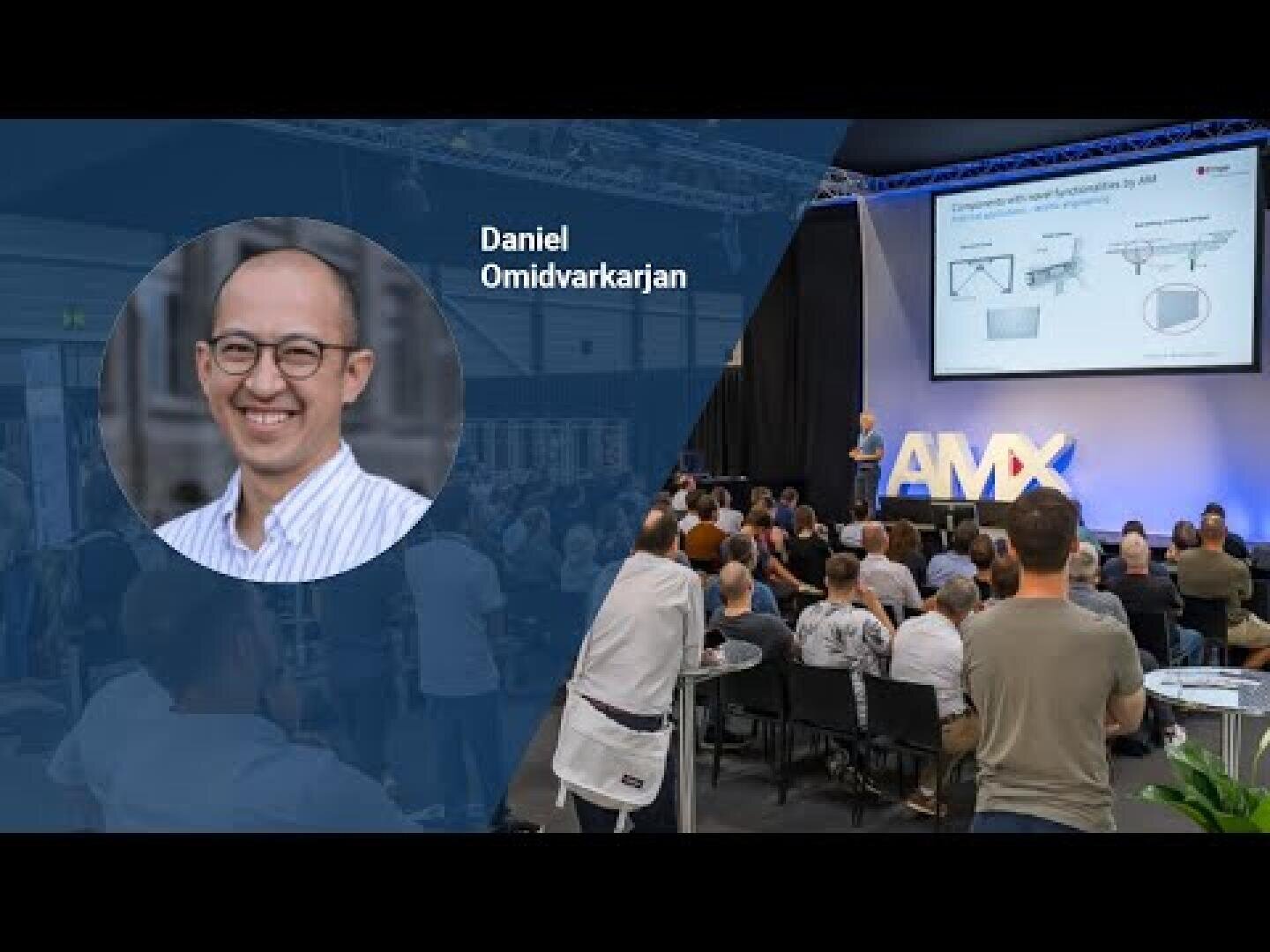 Ein Hauptredner spricht auf der Bühne vor einem sitzenden Publikum auf einer Konferenz. Ein Overlay zeigt einen lächelnden Mann und Text: Daniel Omidvarkarjan. Auf einem großen Bildschirm werden Diagramme angezeigt, und AMX ist auf der Bühne zu sehen.