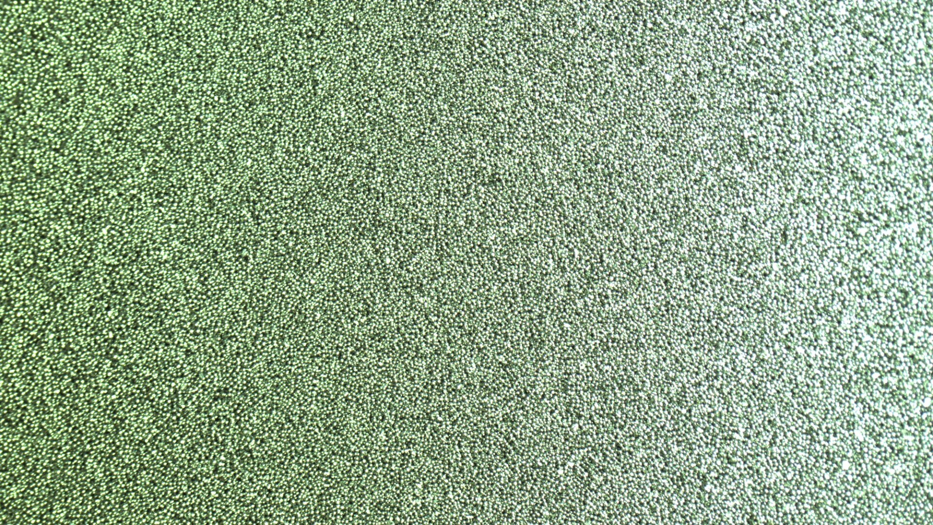 Close-up of a textured green surface with a shimmering, glittery appearance, creating a sparkling and metallic effect.