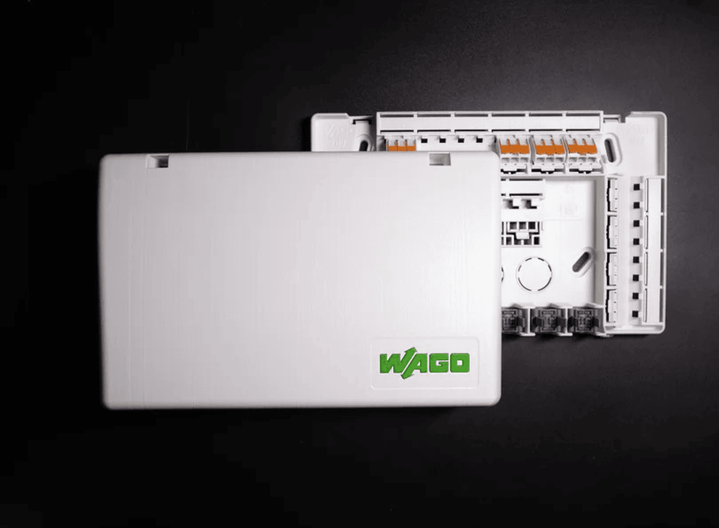 A white, rectangular WAGO electrical connection box with a partially open lid that reveals the internal wiring terminals, on a black background.