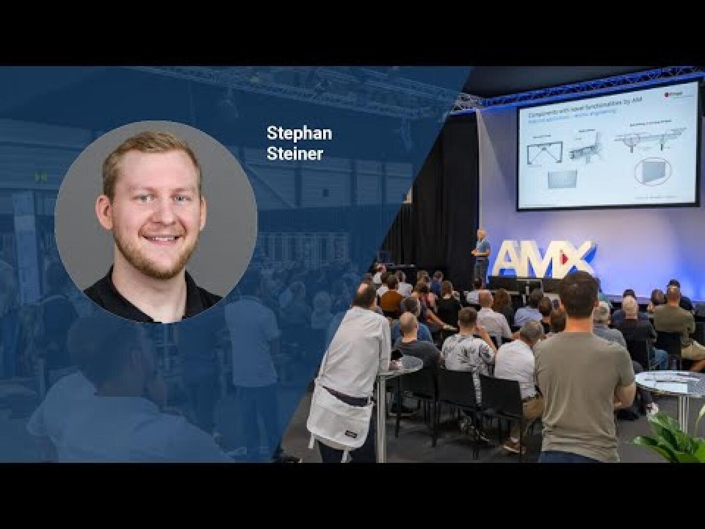 Ein Mann spricht auf der Bühne zu einem Publikum bei einer Konferenz. Auf einem großen Bildschirm werden Diagramme angezeigt. Ein Overlay zeigt ein Porträt von Stephan Steiner mit seinem Namen auf der linken Seite des Bildes.