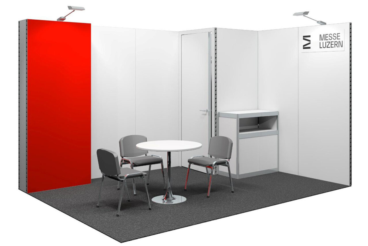 Ein schlichter Messestand mit einem runden Tisch, vier grauen Stühlen, einem weißen Aufbewahrungsschrank, weißen Wänden, einer roten Wandfläche und einem Schild mit der Aufschrift „Messe Luzern“. Deckenleuchten beleuchten den Raum.